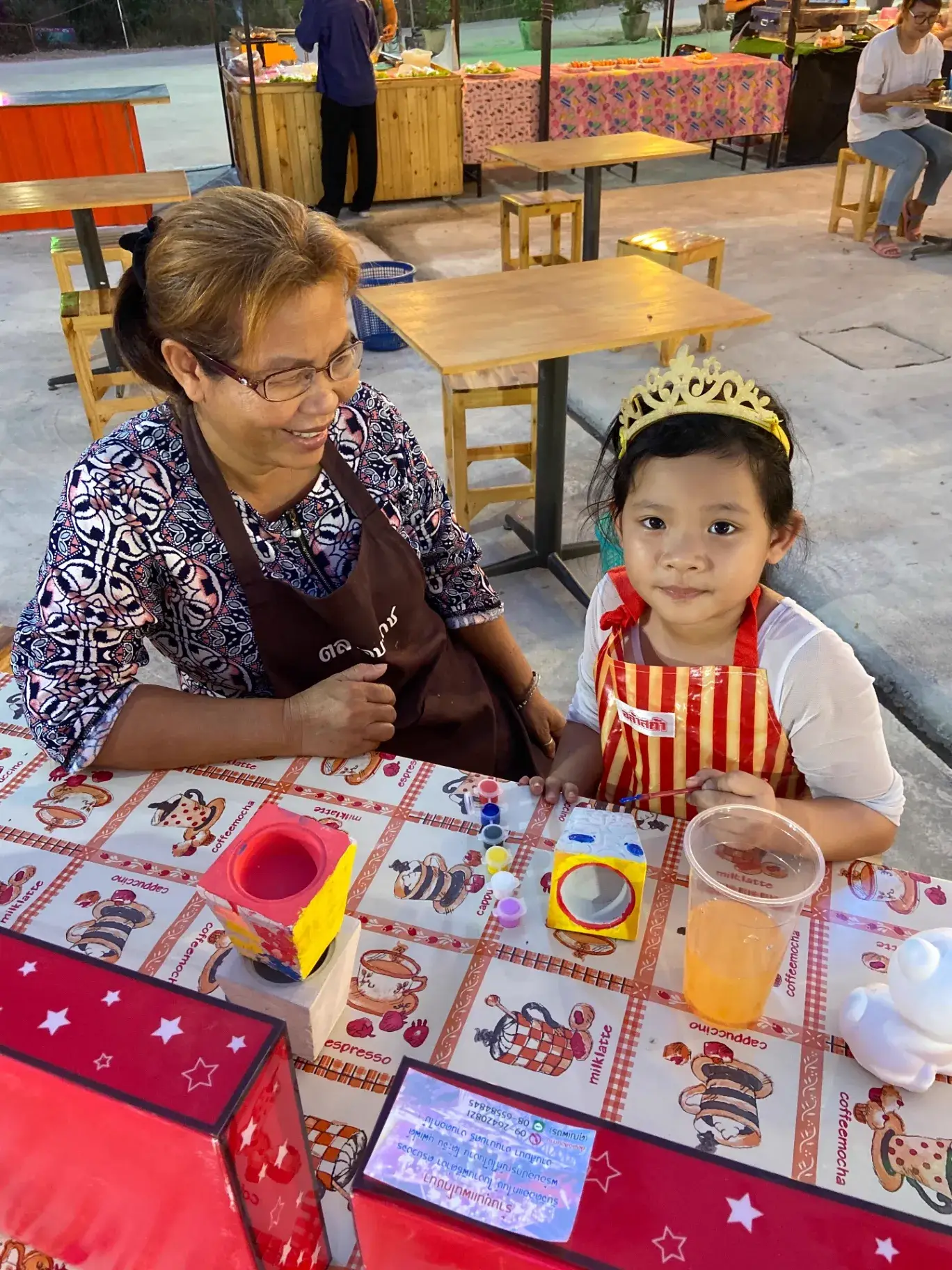 A young child painting alongside an elder mentor